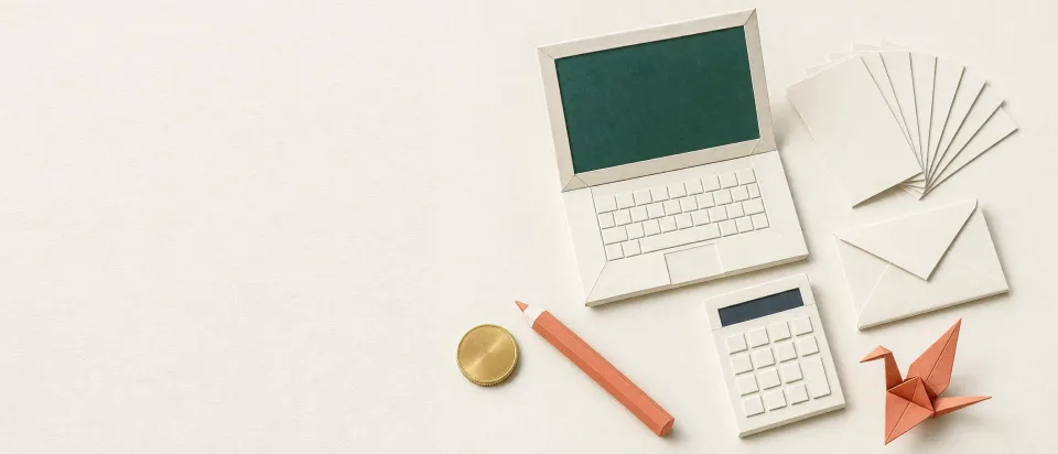 A folded-paper laptop, calculator, envelopes and a paper crane on a white desk